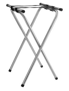 Foldable metal luggage rack with crossed legs and black end caps, used to hold a suitcase.